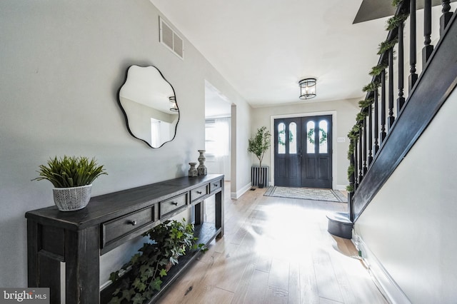 foyer entrance featuring radiator heating unit and light wood-type flooring