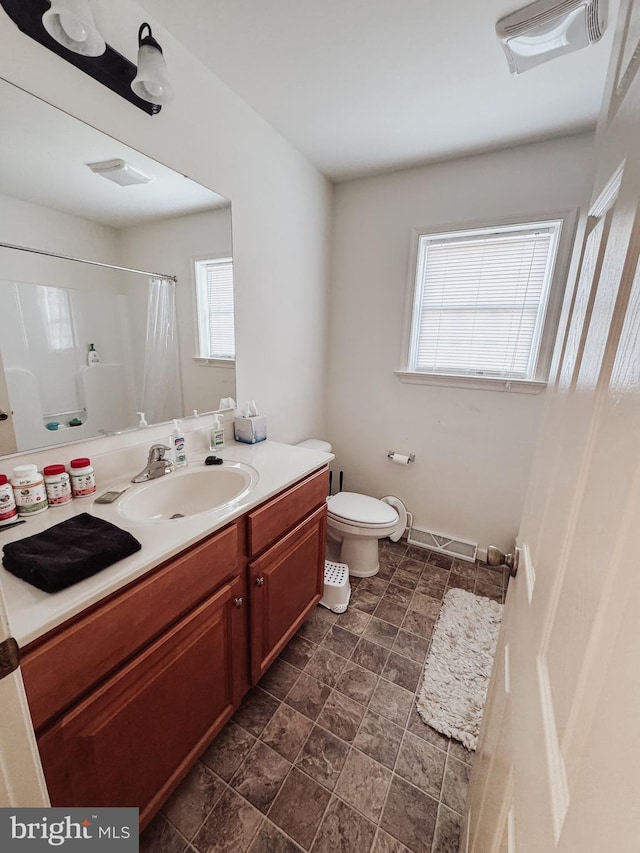 bathroom featuring vanity, toilet, a wealth of natural light, and curtained shower