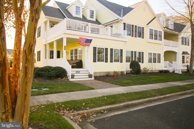 view of front of property featuring a balcony and a front lawn