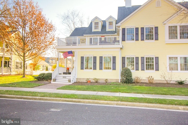 view of front of property with a balcony and a front yard