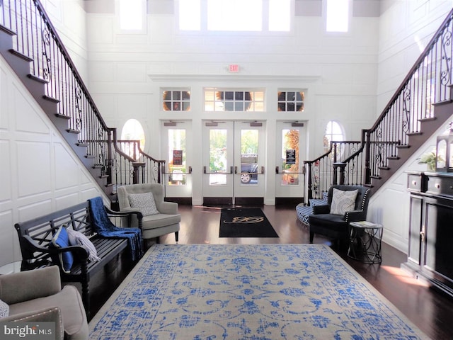 living room featuring a towering ceiling, dark wood-type flooring, and french doors