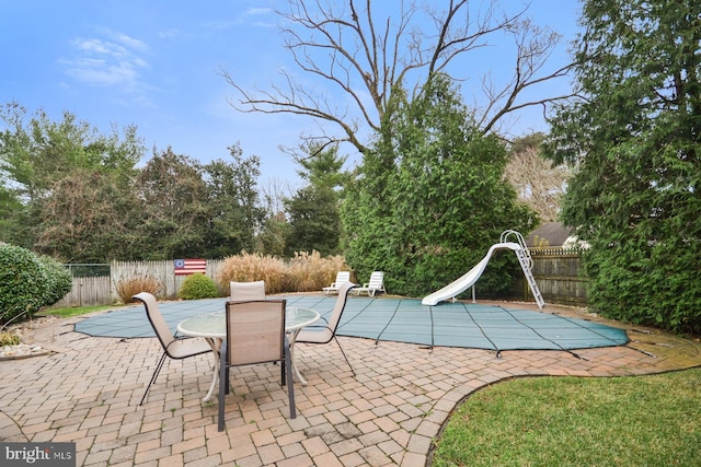 view of swimming pool with a water slide and a patio