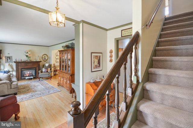 stairway featuring hardwood / wood-style flooring, ornamental molding, and a chandelier