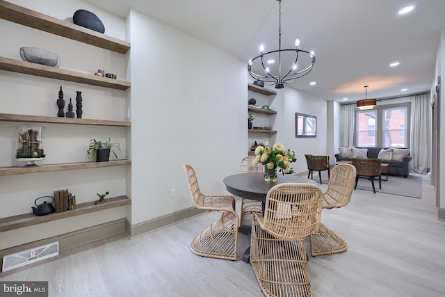 dining room featuring a chandelier, built in shelves, and light wood-type flooring