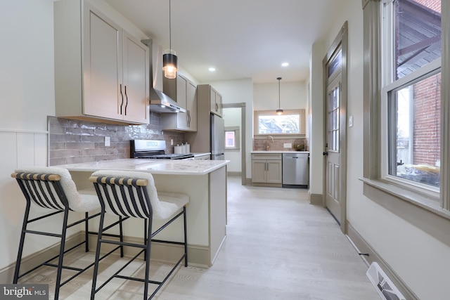 kitchen featuring pendant lighting, a kitchen breakfast bar, gray cabinets, kitchen peninsula, and stainless steel appliances