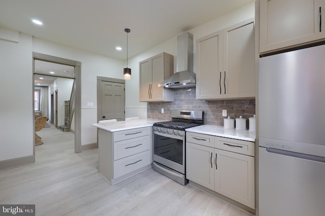 kitchen with kitchen peninsula, wall chimney exhaust hood, gray cabinetry, stainless steel gas stove, and white fridge