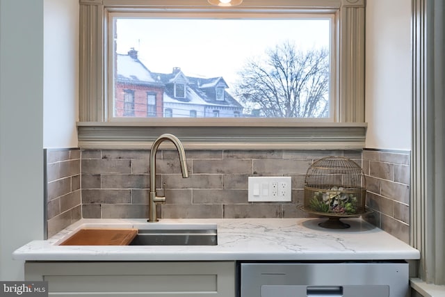 interior details featuring light stone countertops, tasteful backsplash, and sink