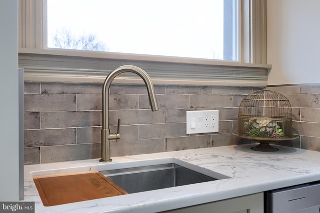 interior details with backsplash, light stone countertops, and sink