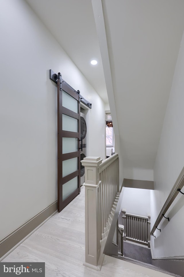 stairway featuring a barn door and wood-type flooring