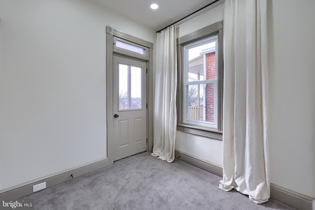 entryway with a wealth of natural light and light carpet