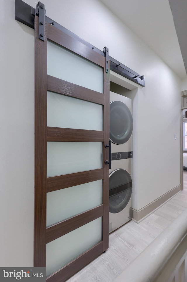 interior details with hardwood / wood-style floors and stacked washing maching and dryer