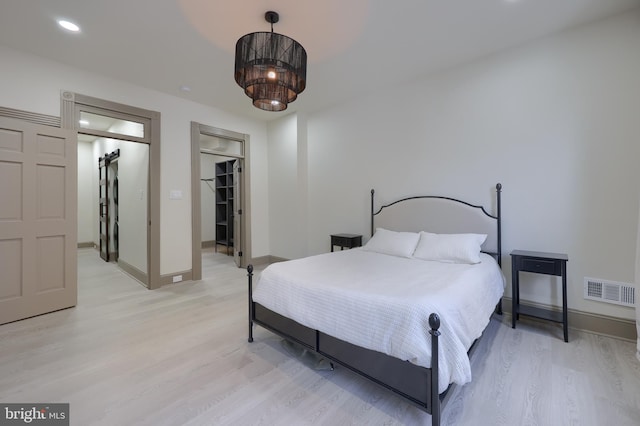 bedroom featuring a closet, a spacious closet, and light hardwood / wood-style flooring