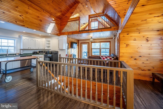 interior space featuring dark wood-type flooring, high vaulted ceiling, sink, wooden walls, and wood ceiling