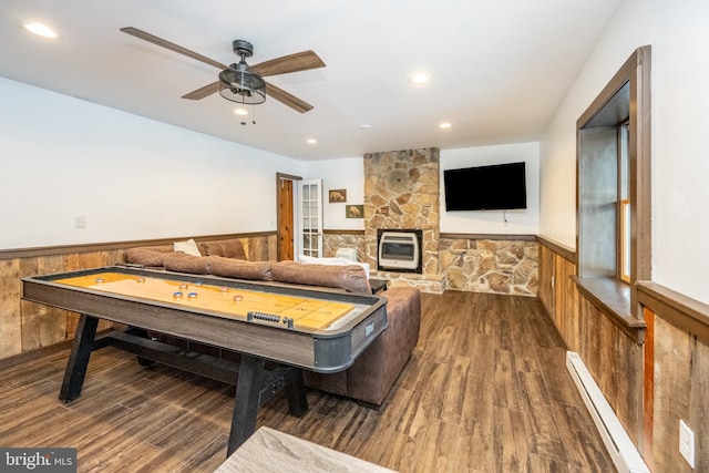 playroom with heating unit, dark hardwood / wood-style floors, ceiling fan, and a baseboard heating unit