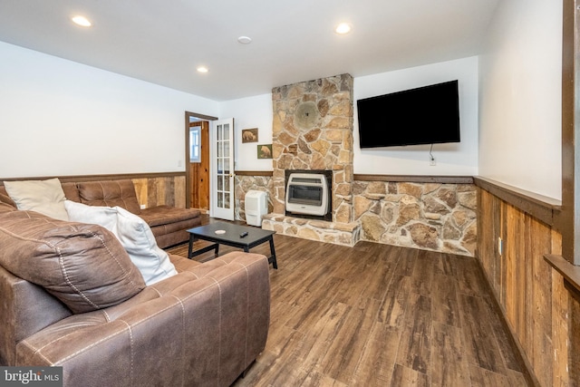 living room with heating unit, wooden walls, and wood-type flooring