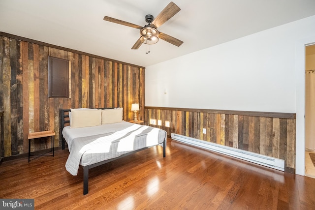 bedroom featuring hardwood / wood-style flooring, ceiling fan, baseboard heating, and electric panel