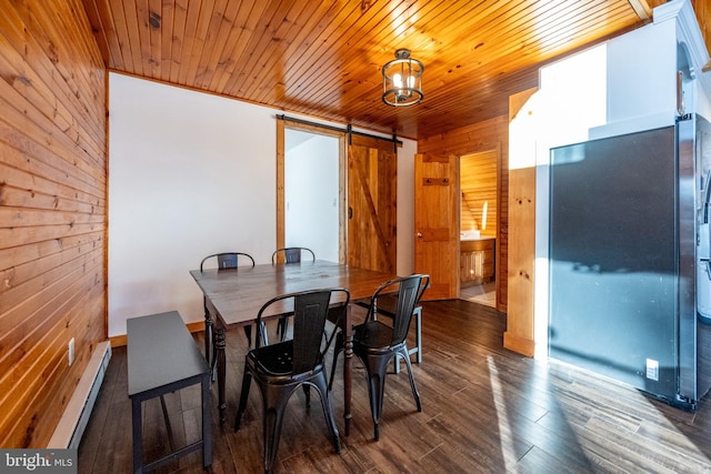 dining area with dark hardwood / wood-style flooring, a barn door, a baseboard heating unit, and wood walls