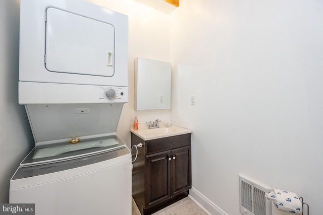 laundry area featuring stacked washer / dryer, sink, and cabinets