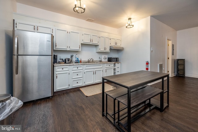 kitchen with white cabinetry, sink, hanging light fixtures, stainless steel appliances, and dark hardwood / wood-style floors