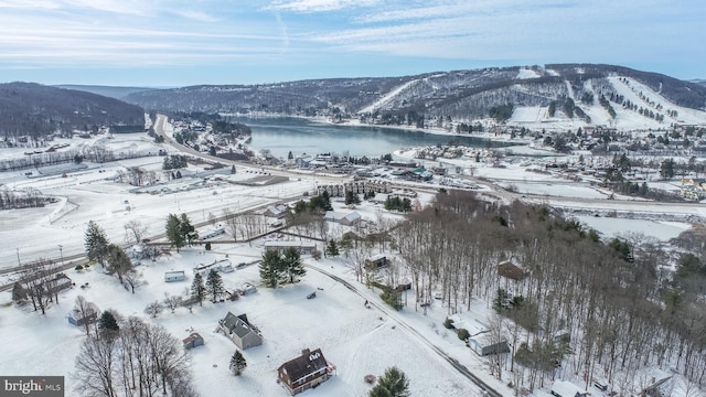 snowy aerial view featuring a water and mountain view