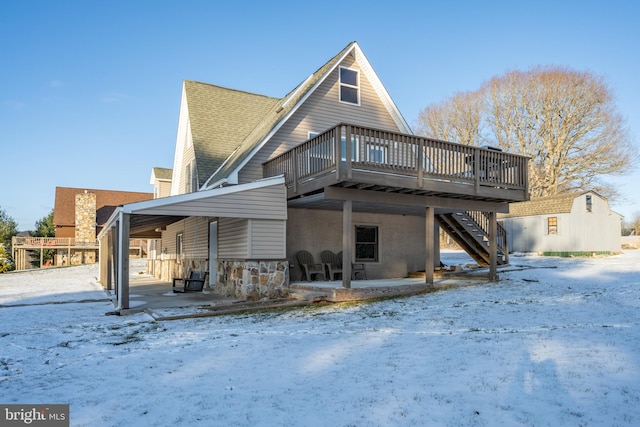 snow covered rear of property with a patio area and a deck