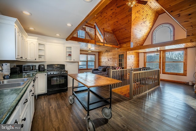 kitchen featuring black range with gas cooktop, ceiling fan, sink, white cabinetry, and wood walls