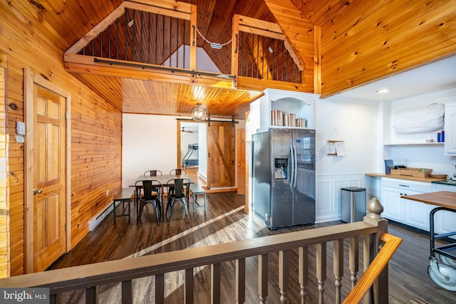 kitchen with white cabinetry, dark wood-type flooring, a barn door, stainless steel fridge, and wood ceiling