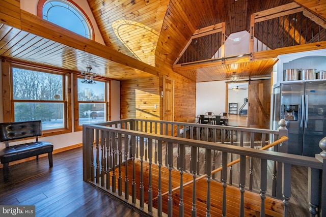 hallway featuring wooden walls, wood-type flooring, high vaulted ceiling, and a chandelier