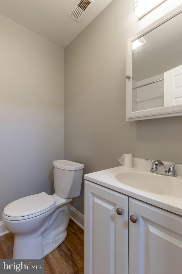 bathroom with toilet, hardwood / wood-style flooring, and vanity