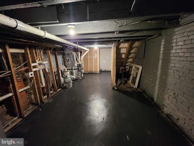 basement featuring heating unit and brick wall