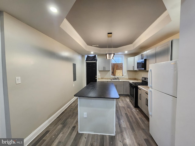 kitchen featuring appliances with stainless steel finishes, a tray ceiling, a kitchen island, and decorative light fixtures