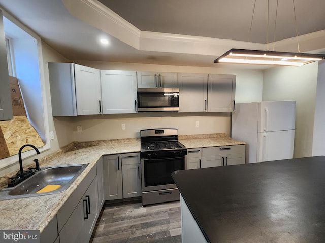 kitchen featuring appliances with stainless steel finishes, ornamental molding, gray cabinetry, sink, and wood-type flooring