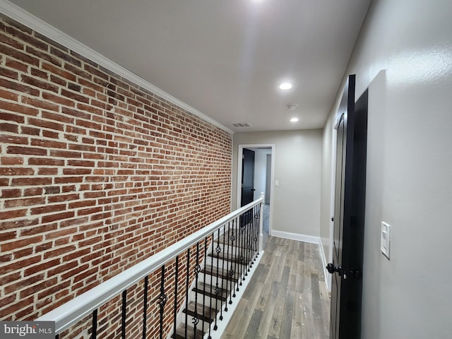 hall featuring hardwood / wood-style flooring, ornamental molding, and brick wall