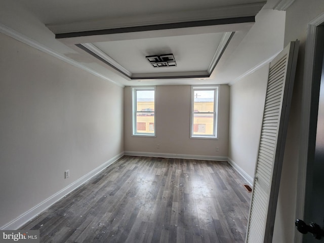 unfurnished room featuring dark wood-type flooring, a raised ceiling, and crown molding