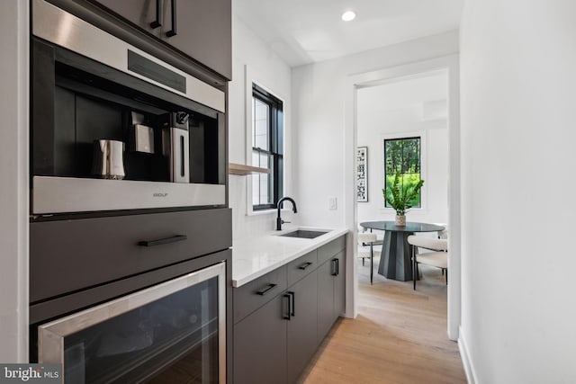 kitchen with gray cabinetry, light stone countertops, sink, and light hardwood / wood-style flooring