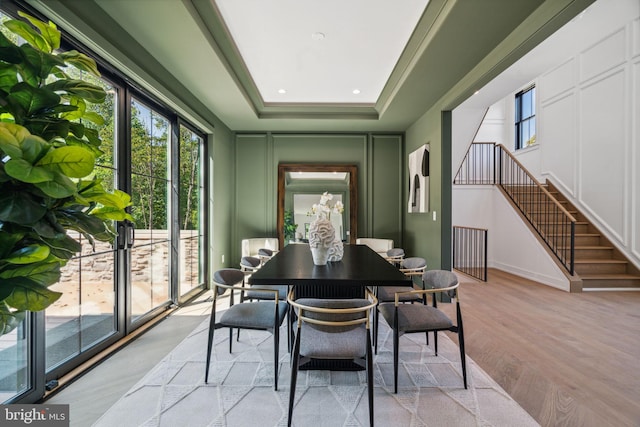 dining area with light hardwood / wood-style floors and a tray ceiling