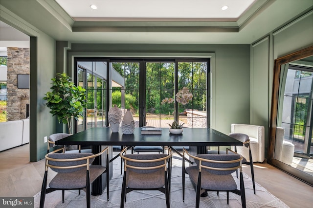 dining room with crown molding, light hardwood / wood-style flooring, and a tray ceiling