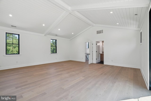 unfurnished room featuring light wood-type flooring, lofted ceiling with beams, and a healthy amount of sunlight