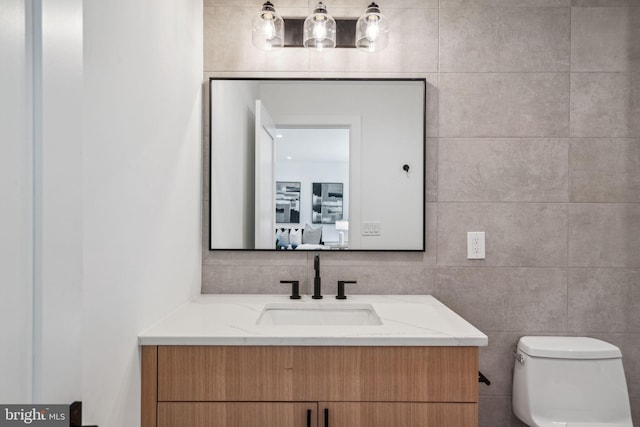 bathroom with vanity, tile walls, and toilet