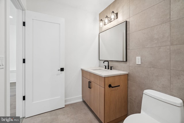 bathroom featuring tile patterned floors, vanity, toilet, and tile walls