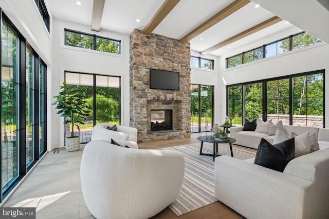 living room with beam ceiling, a healthy amount of sunlight, a fireplace, and a high ceiling