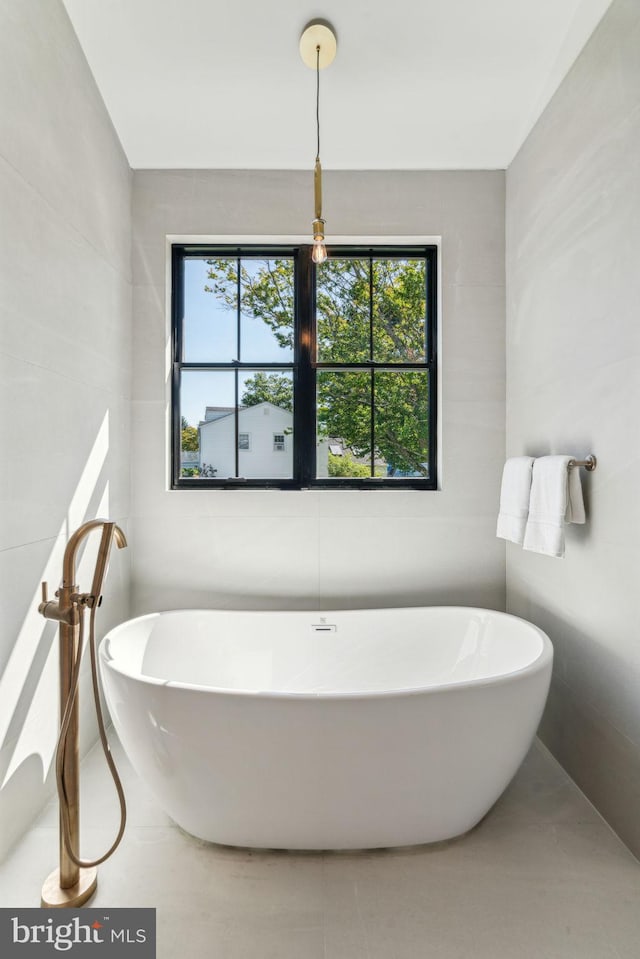 bathroom with a washtub and tile walls