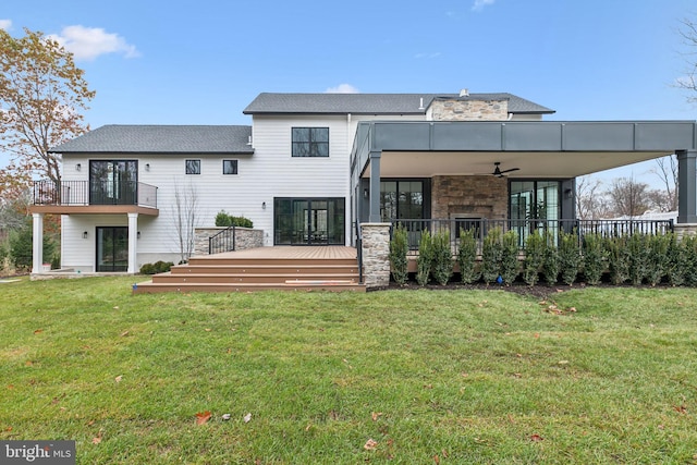 back of property with a deck, ceiling fan, and a lawn