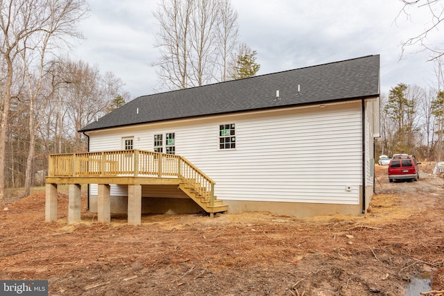 back of property featuring a shingled roof and a deck