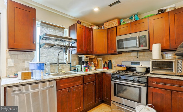 kitchen with appliances with stainless steel finishes, tasteful backsplash, light stone countertops, and light tile patterned floors