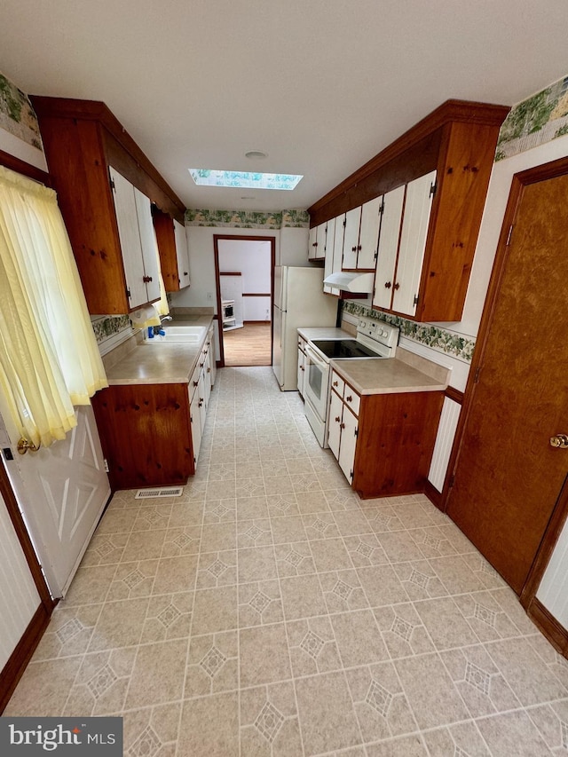 kitchen with a skylight, sink, and white appliances