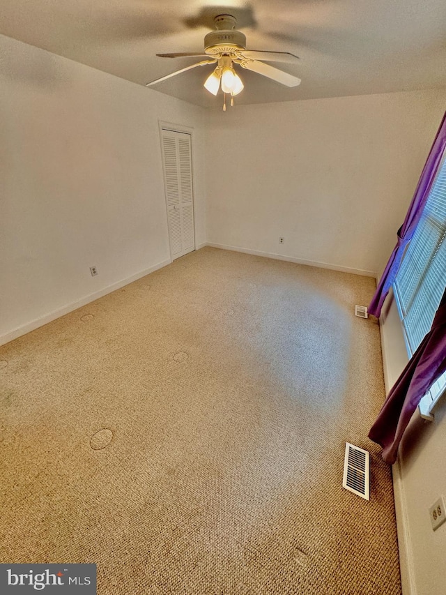 carpeted spare room with ceiling fan