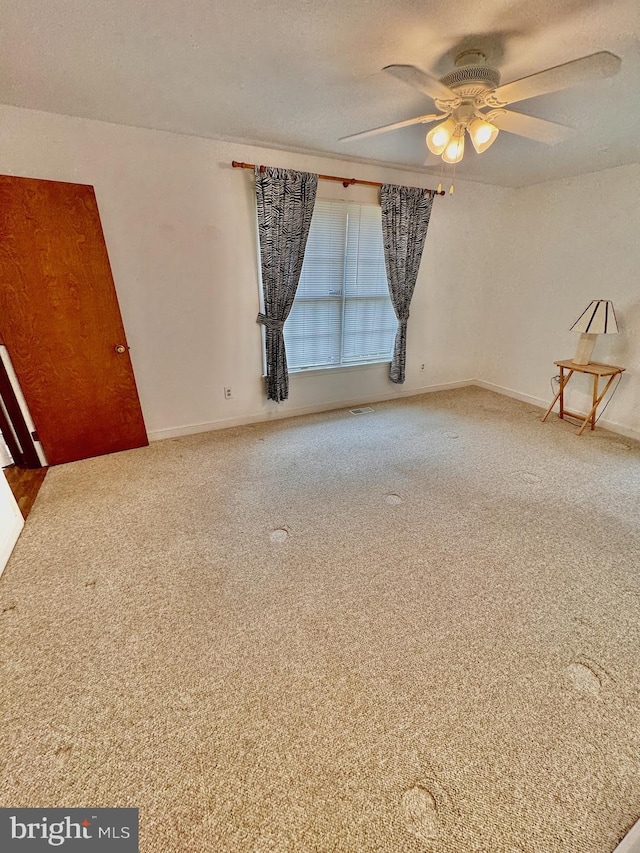 carpeted spare room featuring ceiling fan and a textured ceiling