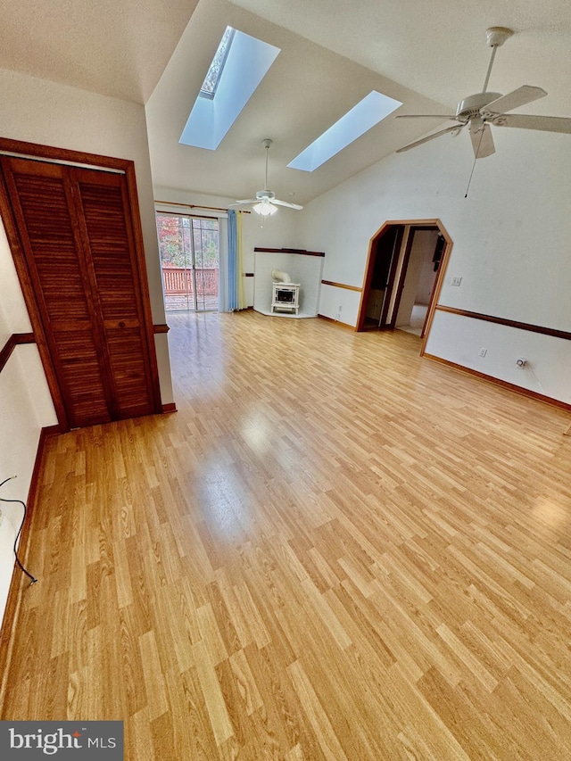 unfurnished living room with lofted ceiling with skylight, ceiling fan, and light wood-type flooring