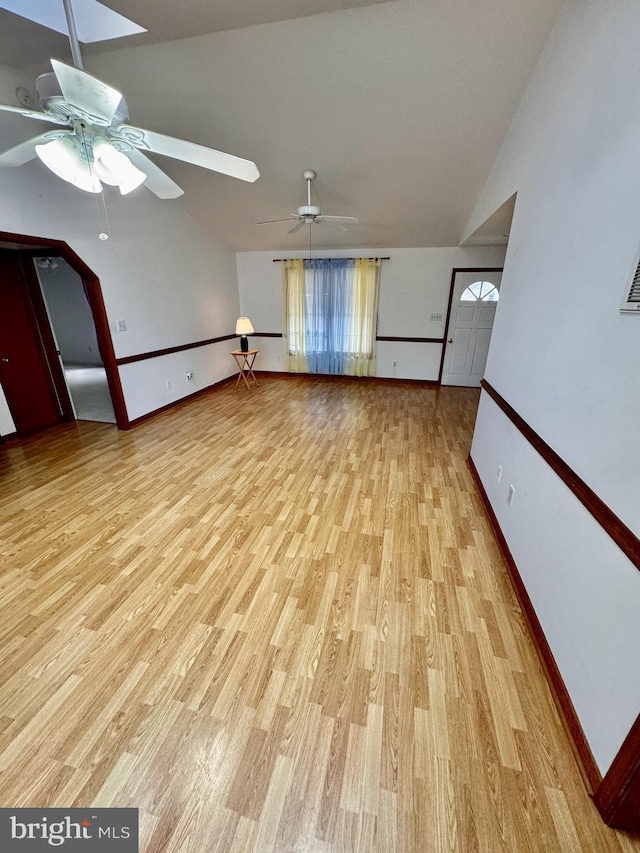 unfurnished living room with light wood-type flooring, vaulted ceiling, a wealth of natural light, and ceiling fan